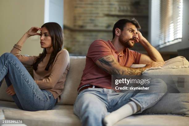 displeased couple ignoring each other in the living room. - menselijke relaties stockfoto's en -beelden