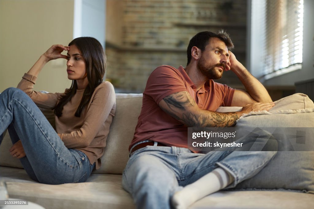 Displeased couple ignoring each other in the living room.