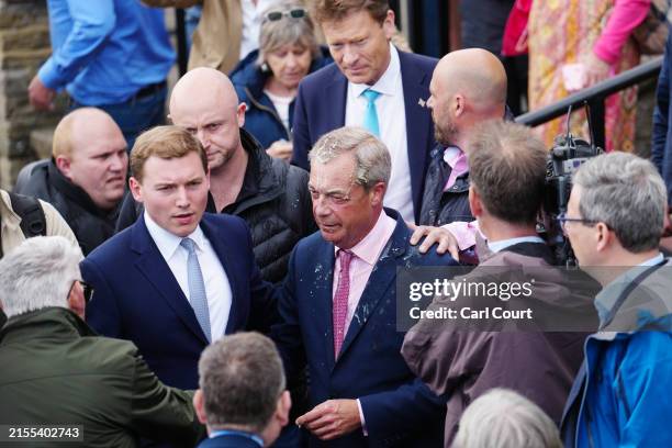 George Cottrell looks on as Reform UK party leader Nigel Farage reacts after a woman threw what appeared to be a milkshake over him, as he launches...