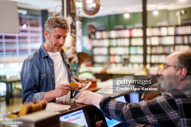 kontaktloses bezahlen in der buchhandlung mit kreditkarte. - buchhandlung stock-fotos und bilder