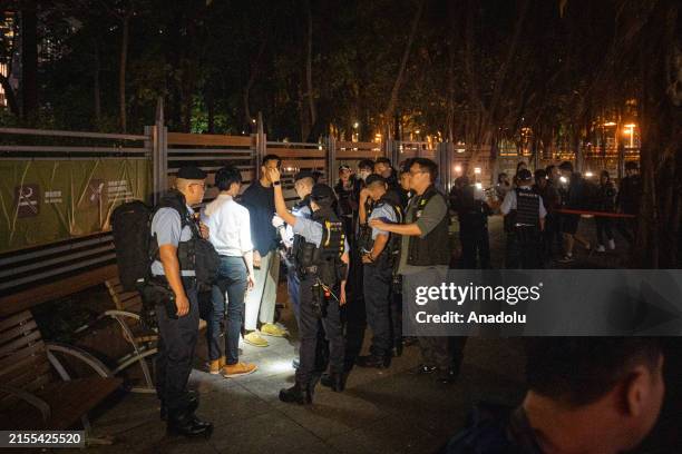 Police officers search some people as members of the media gather at Victoria Park where people traditionally gathered annually to mourn the victims...
