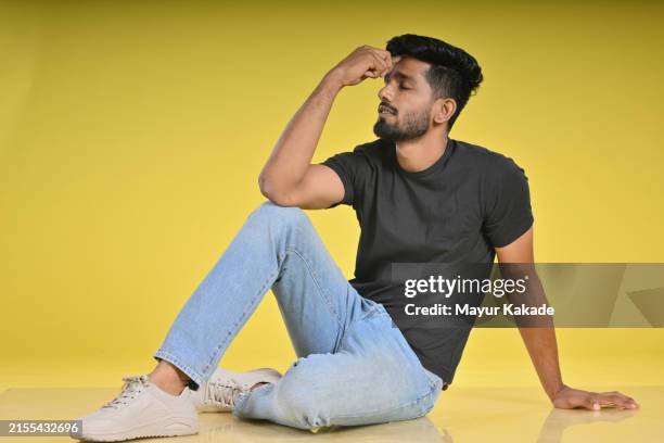studio portrait of a serious young man thinking deep - sitting on ground stock pictures, royalty-free photos & images