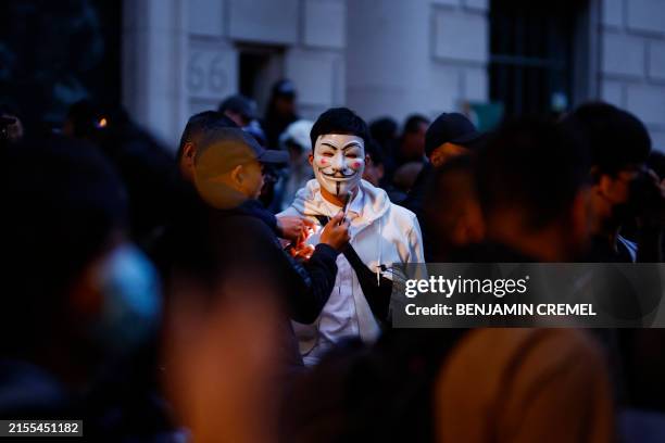 Person wearing the Guy Fawkes mask, also known as the V for Vendetta mask, or Anonymous mask, takes part in a vigil outside the China's embassy, in...
