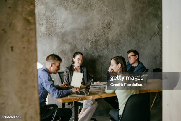 a man and a two woman working in an office at a table - immobilienbüro stock-fotos und bilder