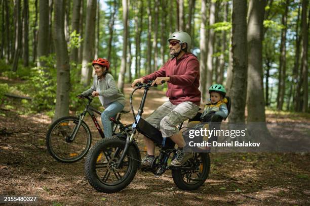 eco tourism. family ride e-bike in forest with kid. - family day stock pictures, royalty-free photos & images