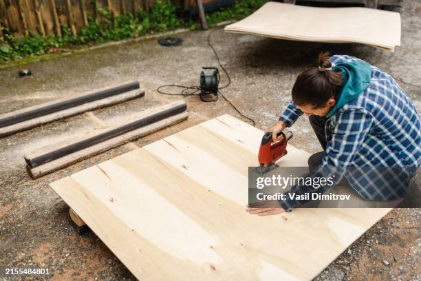 carpentry work. young man cutting plywood. - plywood stock pictures, royalty-free photos & images
