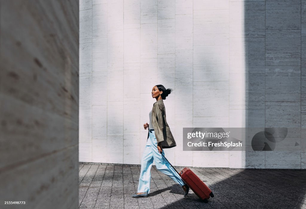 Confident Woman Walking with Red Suitcase in Modern Urban Setting
