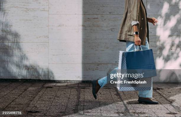 donna che cammina con le borse della spesa sulla strada della città - shopping foto e immagini stock