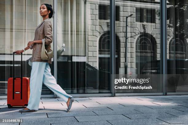 businesswoman walking with rolling luggage in city - mala de rodinhas imagens e fotografias de stock