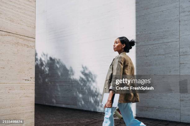 confident businesswoman walking outdoors with tablet - black blazer imagens e fotografias de stock