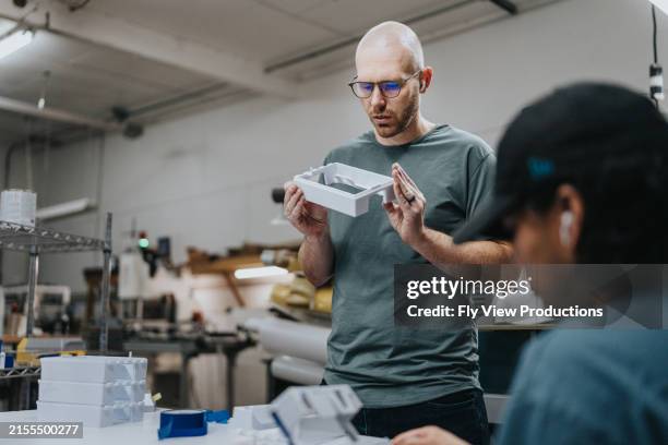 man holds up prototype model while at work - prototype stock pictures, royalty-free photos & images