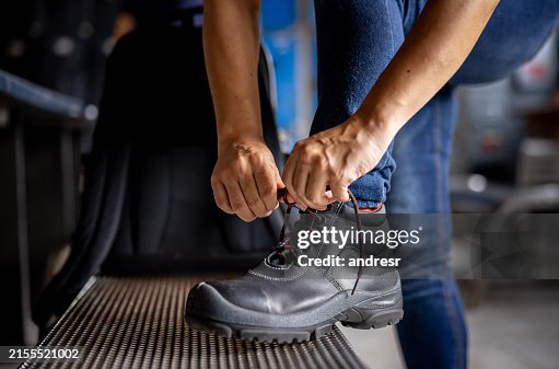 Manufacturing worker tying the shoelaces on his work boots Manufacturing worker tying the shoelaces on his work boots