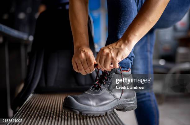 manufacturing worker tying the shoelaces on his work boots - tying boots stock pictures, royalty-free photos & images