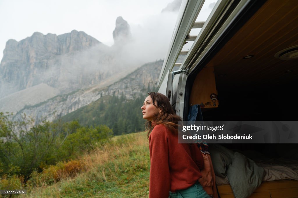 Woman looking out of camper van enjoying beautiful scenery of Dolomites