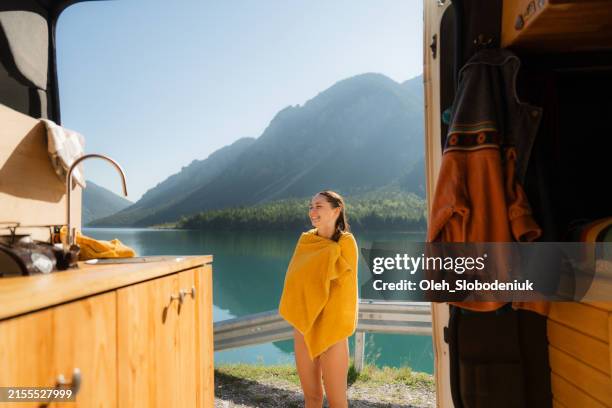 woman after swim in mountain lake standing near camper van - caravan stockfoto's en -beelden