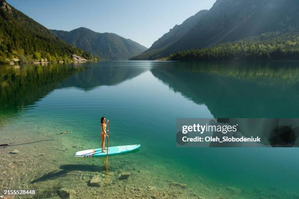 femme sup embarquant sur un lac de montagne dans les alpes - état fédéré du tyrol photos et images de collection