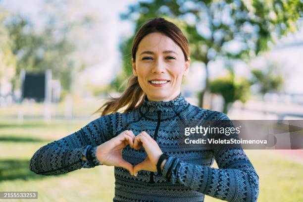 portrait of a sporty young woman exercising outdoors. - hand heart stock pictures, royalty-free photos & images