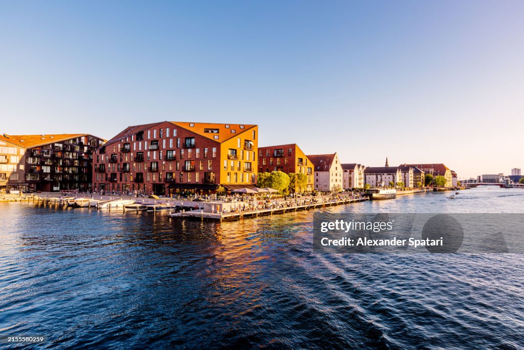 Christianshavn waterfront with new apartment buildings and crowd of people relaxing by the river, Copenhagen, Denmark