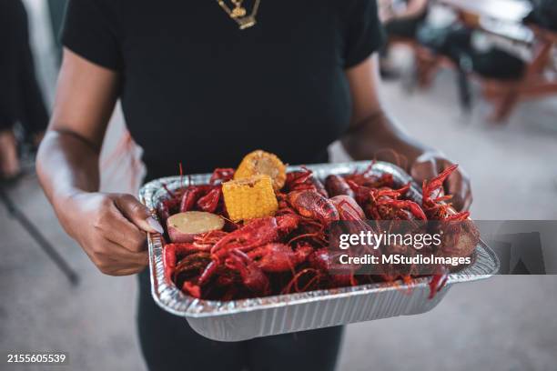 persona sosteniendo bandeja de cangrejo cajún con maíz y papas - sur de eeuu fotografías e imágenes de stock