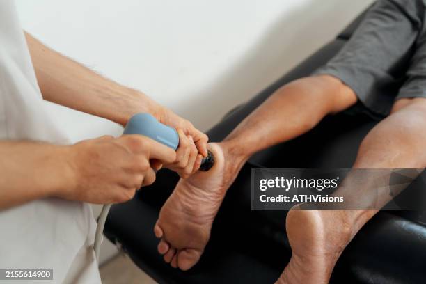 physical therapist using shockwave therapy on patient foot - shockwave therapy stock pictures, royalty-free photos & images