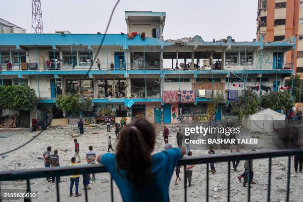 Palestinian girl watches as others check a UN-school housing displaced people that was hit during Israeli bombardment in Nuseirat, in the central...