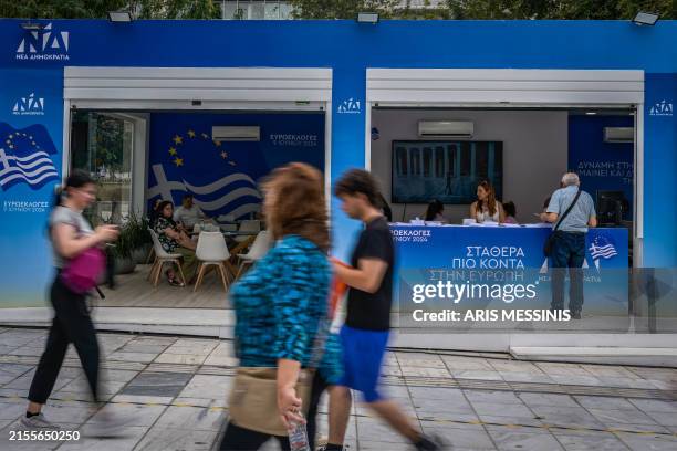 Pedestrians pass by a kiosk of the ruling New Democracy conservative party in central Athens on June 6 ahead of the European elections that will take...
