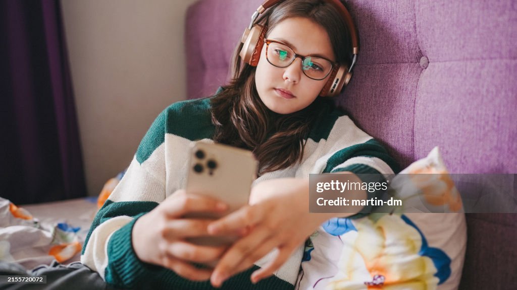 Kid in bed watching viral videos on smartphone