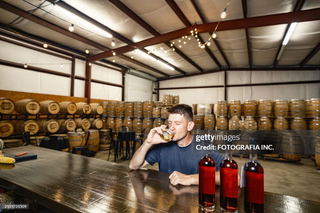 Mid adult male whisky distiller tasting his whisky at distillery bar