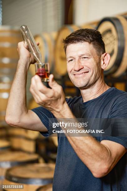 mid adult male whisky distiller tasting his whisky at distillery bar - whiskey tasting stock pictures, royalty-free photos & images