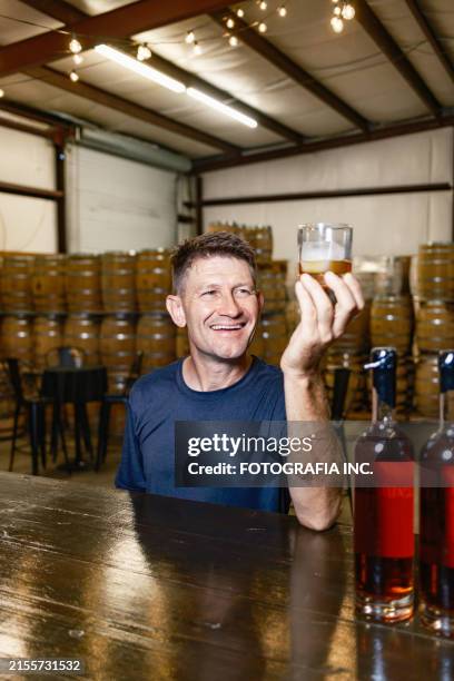 mid adult male whisky distiller tasting his whisky at distillery bar - whiskey tasting stock pictures, royalty-free photos & images