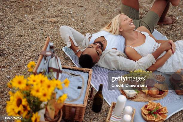 happy couple laying down on their picnic blanket - couple picnic stock pictures, royalty-free photos & images