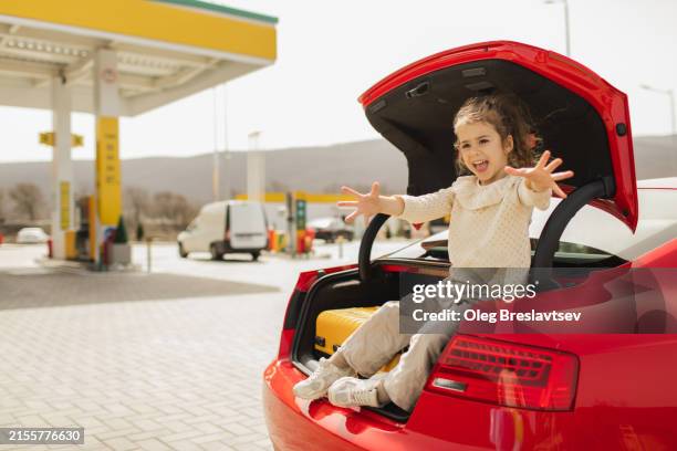 laughing mischief baby girl having fun in car boot on the stop in road trip - girl gas station stock pictures, royalty-free photos & images