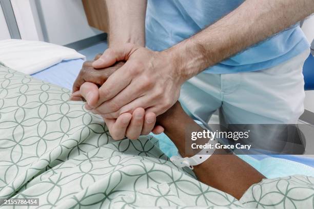 man comforts woman at her bedside in hospital - namensband stock-fotos und bilder