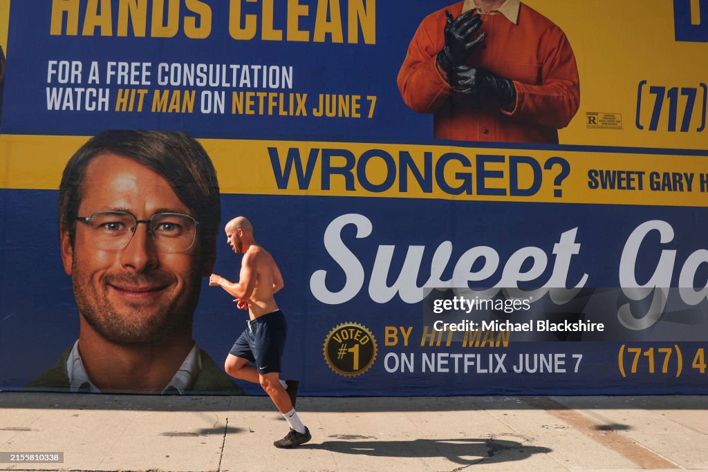 A man jogs by the new Netflix movie Hit Man wall poster on Beverly ...