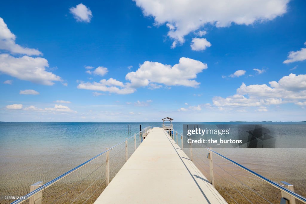 Jetty by the sea against blue sky and clouds