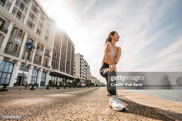 frau dehnen vor dem lauf - joggerin stock-fotos und bilder