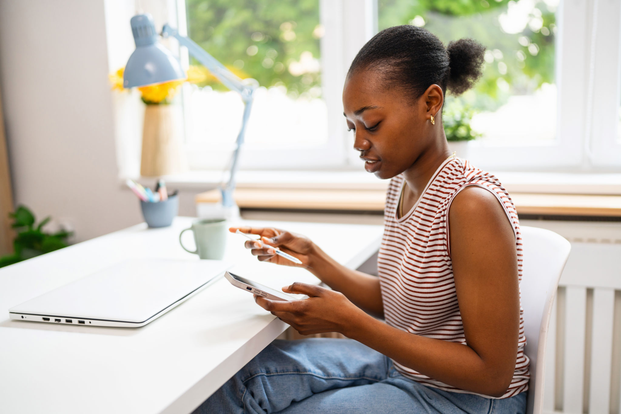 Young woman self-giving an insulin injection and using smart phone while working at her home office Young woman self-giving an insulin injection and using smart phone while working at her home office
