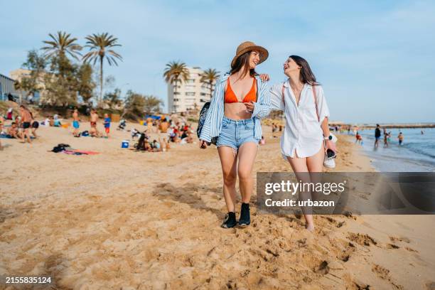 two female friends walking on the beach in palma de mallorca in spain - majorca stock pictures, royalty-free photos & images