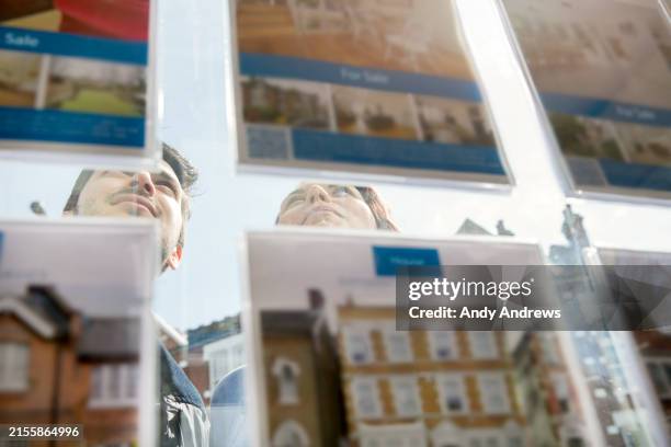 couple looking at property at real estate agent's office - window stock pictures, royalty-free photos & images