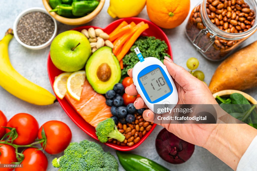Mano sosteniendo el glucómetro en el fondo de la comida saludable