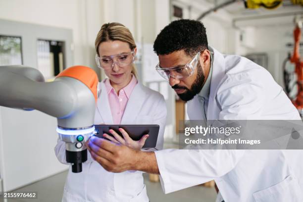 robotic engineer colleagues working on robotic knee replacement surgery project, adjusting robots settings. concept of robotics, engineering and computer science in healthcare. - medizinisches gerät stock-fotos und bilder