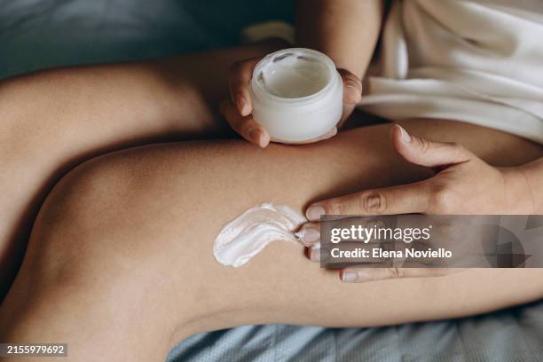 a woman applies moisturizing anti-cellulite cream to her legs , daily skin and body care routine - cellulite stock pictures, royalty-free photos & images