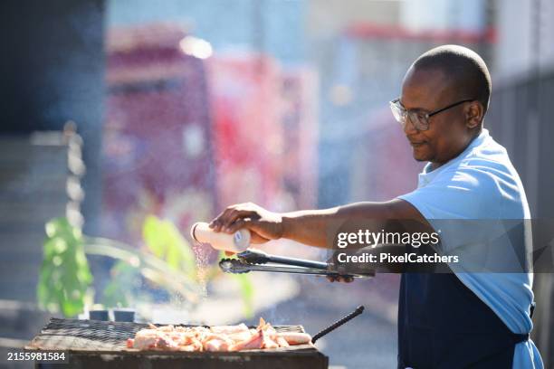 a chef ads spices to an outdoor barbecue in the inner city - sprinkling stock pictures, royalty-free photos & images