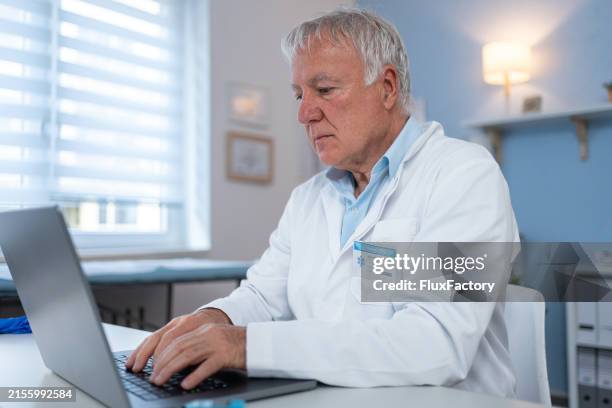a doctor uses his laptop - kabinet dokter stockfoto's en -beelden