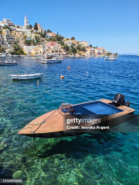 simple modern wooden boat floating on colourful blue green water - simi stock-fotos und bilder