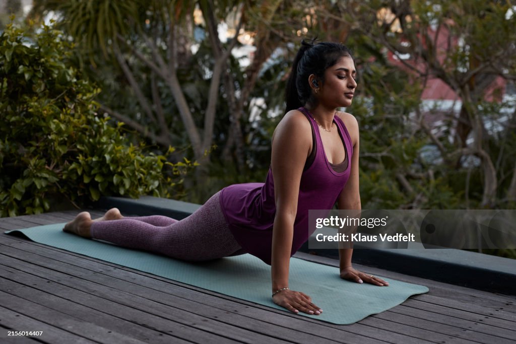 Young woman practicing cobra pose yoga with eyes closed