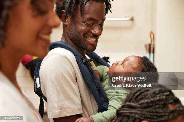 cheerful young man with carrying toddler son by woman - modern manhood stock pictures, royalty-free photos & images