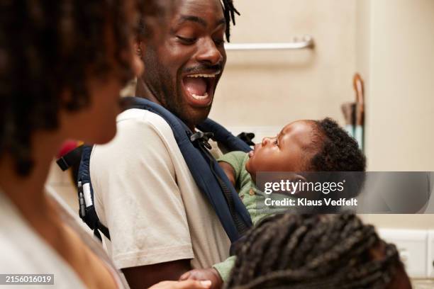 cheerful young man with carrying baby boy by woman - jeune famille photos et images de collection