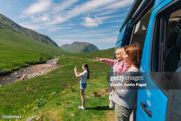 a mature woman enjoys the view of the scottish highlands with her two daughters whilst on a staycation trip in their campervan - road trip stock pictures, royalty-free photos & images