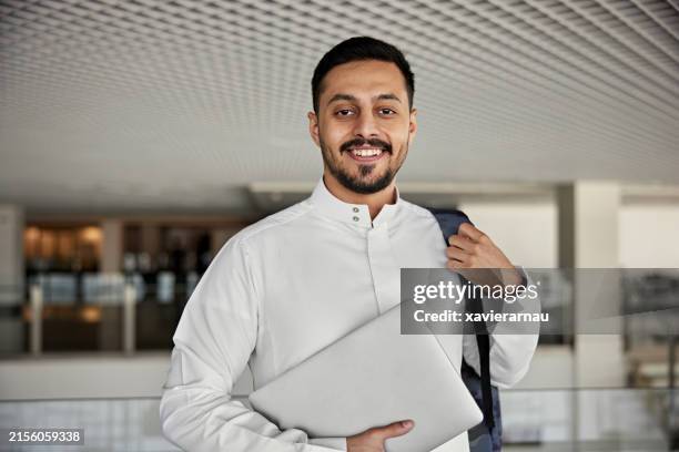jeune étudiant souriant avec ordinateur portable et sac à dos - dishdasha photos et images de collection